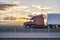 Burgundy big rig semi truck with grille guard and high cab spoiler transporting cargo in dry van semi trailer driving on the road
