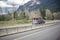 Burgundy classic big rig semi truck with empty car hauler semi trailer driving on the winding highway road in Columbia Gorge area