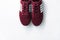 Burgundy sneakers on a white background with nature light shadows