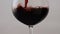 Burgundy wine pouring glass goblet in super slow motion closeup. Drink flowing