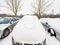 Buried car by snow with painted heart. Cloudy winter day