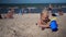 Buried little girl take toy bucket with water from mother and pour it on sand