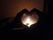 Buring candle, two hands making symbol of LOve in Dark room