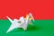 Burkina Faso flag depicted on paper origami crane wing. Handmade arts concept