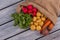 Burlap bag with various vegetables on wood.