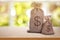 Burlap bags with dollar signs on wooden table indoors. Space for text