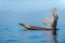 Burmese fisherman dressed in traditional style standing at the back of the boat