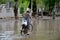 Burmese girl riding bicycle in flood area