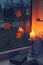 Burn candle front of window, fallen leaves and book. Moment of loneliness and autumn melancholy