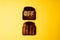 Burn off concept. Two slices of dark burnt charred white bread with word Off on it on yellow background