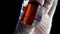 Burned piece of orange mineral. Close-up of gloved hands holding piece of processed amber mineral on black background