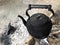 Burned Thai vintage black hot teapot on fire charcoals wood