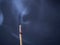 Burning aromatic incense stick with cinder and clouds of smoke on a gray background with copy space.