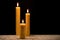 Burning beeswax candles on wooden table. Black background. Copy space for text.