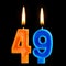 Burning birthday candles in the form of 49 forty nine for cake isolated on black background.