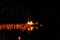 Burning boat and lit paper lanterns floating on the lake water at dark night