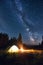 Burning bonfire and tents under bright starry sky on which the Milky Way is clearly visible. Magical sky