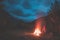 Burning camp fire into remote larch and pine tree woodland with high altitude landscape and dramatic sky at dusk. Summer adventure