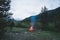 Burning camp fire into remote larch and pine tree woodland with high altitude landscape and dramatic sky at dusk. Summer adventure