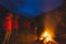 Burning camp fire into remote larch and pine tree woodland with high altitude landscape and dramatic sky at dusk. Summer adventure