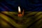 A burning candle against the background of the national flag of Ukraine, yellow-blue, peace in Ukraine