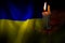 A burning candle against the background of the national flag of Ukraine, yellow-blue, peace in Ukraine