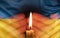 a burning candle against the background of the national flag of Ukraine, yellow-blue, peace in Ukraine