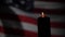 Burning candle against the background of the waving flag of the united states of america in the dark.