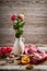 Burning candle, bouquet of flowers in a white vase, scissors, a rope on a wooden background. Postcard.