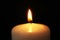 Burning candle on dark background, closeup. Symbol of
