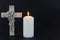 Burning candle on a dark background with an ornate cross. Mourning moment at the end of a life. Last farewell. Copy space. Condole