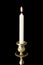 Burning candle in figured gilded candlestick, isolated on black background.
