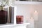 Burning candle, flowers and books on white table indoors