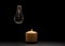 Burning candle near a switched off light bulb in dark home. Blackout, electricity off, load shedding energy crisis or power outage