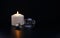 Burning candle near a switched off light bulb in dark home. Blackout, electricity off, load shedding energy crisis or power outage