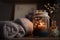 Burning candle in small amber glass jar, flowers of gypsophila and stack knitted seasin sweaters Cozy lifestyle, hygge concept.