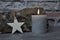 Burning candle, star and wood billet in front of brick wall