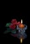 Burning candle and three red roses on a black background