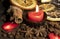 A burning candle , various spices, dried oranges and small meringues on a wooden table top