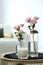 Burning candle and vases with beautiful roses on table indoors. Interior elements