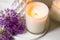 Burning candle and violet allium flowers on white tray