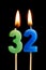 Burning candles in the form of 32 thirty two numbers, dates for cake isolated on black background. The concept of celebrating a