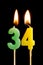 Burning candles in the form of 34 thirty four numbers, dates for cake isolated on black background. The concept of celebrating a