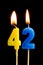 Burning candles in the form of 42 forty two numbers, dates for cake isolated on black background. The concept of celebrating a b