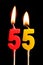 Burning candles in the form of 55 fifty five numbers, dates for cake isolated on black background. The concept of celebrating a