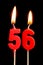 Burning candles in the form of 56 fifty six numbers, dates for cake isolated on black background. The concept of celebrating a b