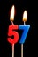 Burning candles in the form of 57 fifty seven numbers, dates for cake isolated on black background. The concept of celebrating a b