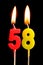 Burning candles in the form of 58 fifty eight numbers, dates for cake isolated on black background. The concept of celebrating a