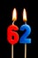 Burning candles in the form of 62 sixty two numbers, dates for cake isolated on black background. The concept of celebrating a b