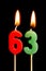 Burning candles in the form of 63 sixty three numbers, dates for cake isolated on black background. The concept of celebrating a